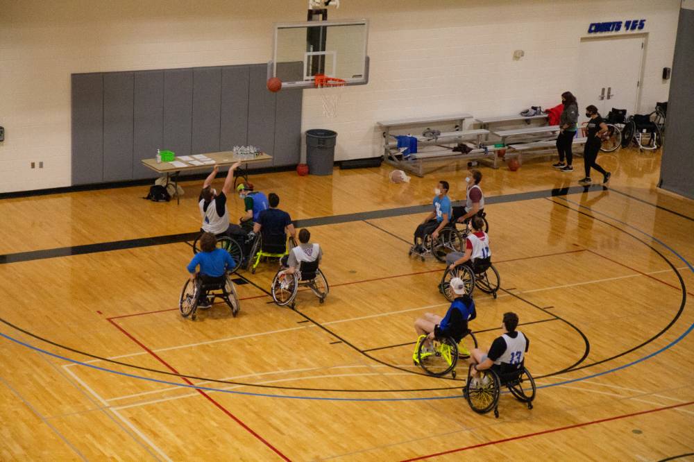 Adult in wheelchair shooting a basketball during a basketball game.